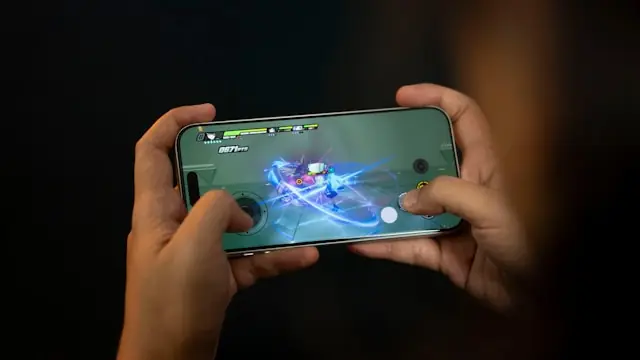 Zwei Hände halten ein Smartphone im Querformat mit einem laufenden Mobile-Game als Bezug zum Nasdaq-Börsengang des Hongkonger Studios DarkIris.