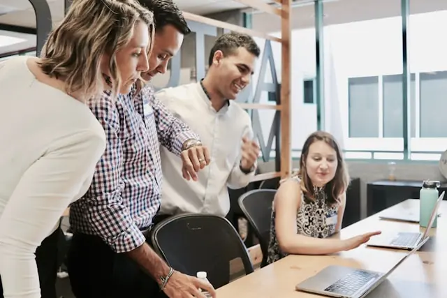 Vier Beschäftigte im Büro blicken gemeinsam auf Laptop-Bildschirme, als Bezug zu starken Quartalszahlen der ManpowerGroup