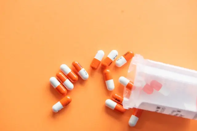 Orange-weiße Kapseln liegen verstreut vor einer umgekippten Tablettendose, im Kontext des Nasdaq-Börsengangs von Hemab Therapeutics.