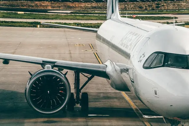 Ein weißes Verkehrsflugzeug mit sichtbarem Triebwerk und Cockpit steht auf dem Rollfeld eines Flughafens.