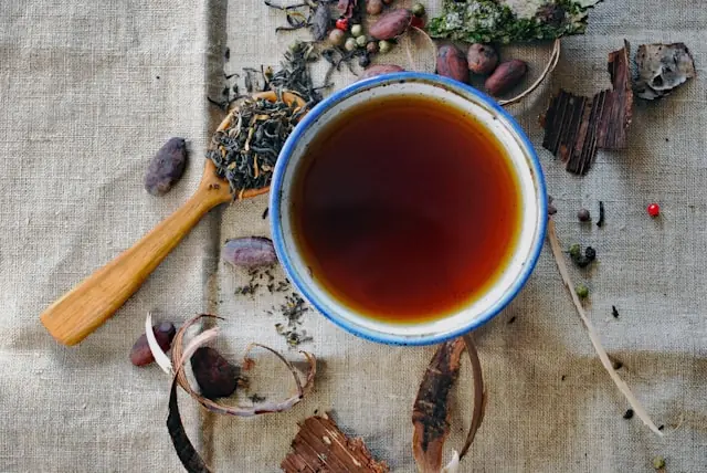 Aufgebrühter Tee in Keramiktasse mit losen Teeblättern und Kräutern als Bezug zum Nasdaq-Börsengang der chinesischen Premium-Teekette Chagee