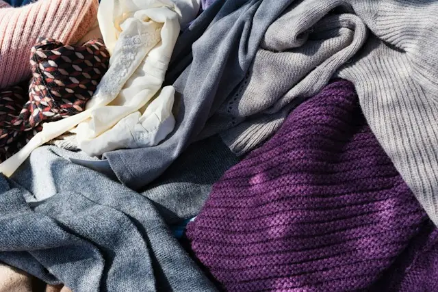 Stapel zerknitterter Strickteile und Blusen in Rosa, Creme, Grau und Violett als Bezug zum Börsengang der Modemarke Reformation