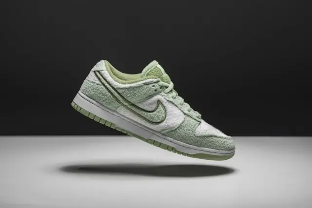 Freigestellter grün-weißer Sneaker mit Frotteeoberfläche vor dunklem Hintergrund im Zusammenhang mit gestaffelten Verkaufsgebühren im Sneaker-Resale