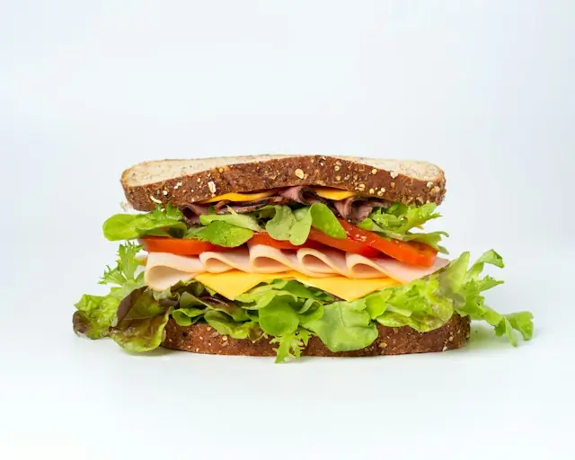 Vollkornsandwich mit Schinken, Roastbeef, Käse, Tomate und Salat vor hellem Hintergrund als Bezug zur Sandwichkette vor dem NYSE-Börsengang
