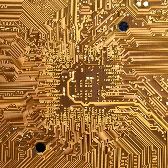 Nahaufnahme einer goldfarbenen Leiterplatte mit verzweigten Leiterbahnen und Lötpunkten, im Kontext des Industrie-Börsengangs von Madison Air.