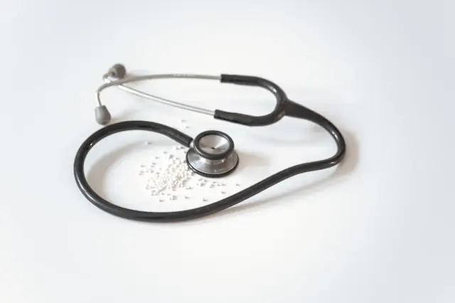 Schwarzes Stethoskop und kleine weiße Tabletten auf weißem Untergrund als Bezug zum US-Krankenversicherer Oscar Health nach dem Kursprung durch Wells-Fargo-Hochstufung.