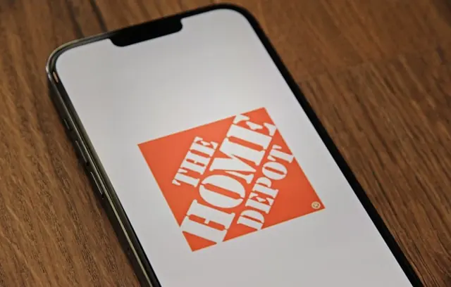Home-Depot-Logo auf dem Display eines Smartphones auf einem Holztisch als Bezug zu den anstehenden Quartalszahlen