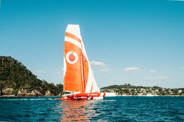 Orange-weißes Segelboot mit Vodafone-Logo am Segel vor bewaldeter Küste als Bezug zum Einstieg von Milliardär Niel als größter Aktionär