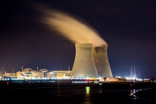 Zwei beleuchtete Kühltürme eines Kernkraftwerks bei Nacht mit aufsteigendem Wasserdampf, im Kontext des schwachen Börsendebüts von X-Energy