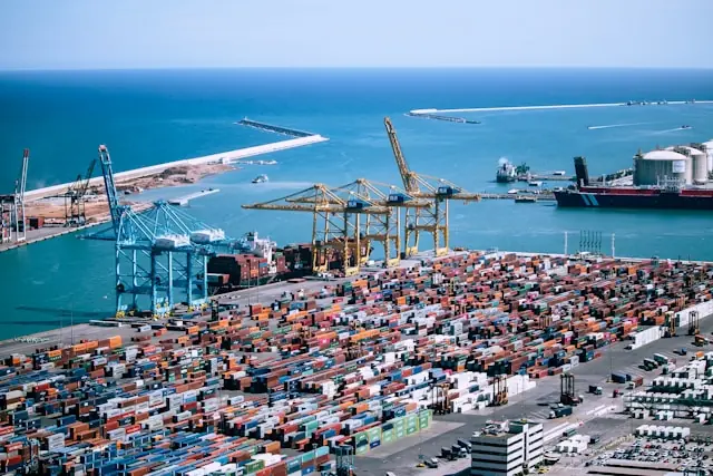 Luftaufnahme eines Containerhafens mit Kränen, Frachtschiffen und gestapelten Containern im Kontext des Börsengangs von Tin Inn