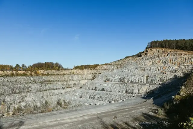 Terrassenförmiger Tagebau mit grauen Felswänden unter blauem Himmel als Bezug zur Silbermine aus Idaho, die an die NYSE geht