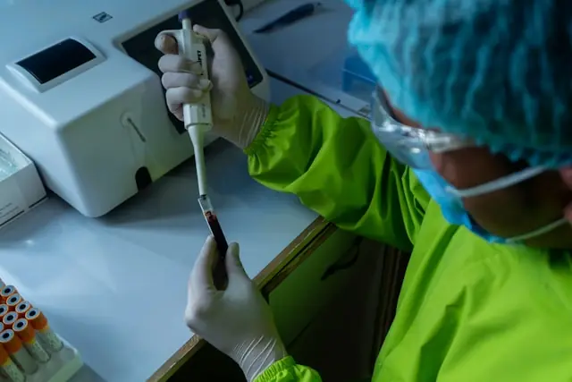 Labormitarbeiter in Schutzausrüstung pipettiert eine Blutprobe im Rahmen molekulardiagnostischer Analysen, wie sie Caris Life Sciences für seinen Nasdaq-Börsengang bewirbt