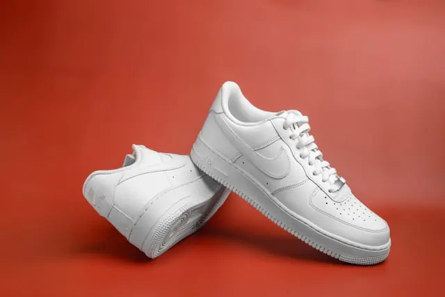 in Paar weiße Sneaker vor rotem Hintergrund als Bezug zum Kurseinbruch bei On Holding, Adidas und Puma