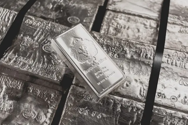 Silberbarren der Marke Scottsdale Silver liegen auf texturierten Feinsilberbarren, fotografiert in Schwarz-Weiß.
