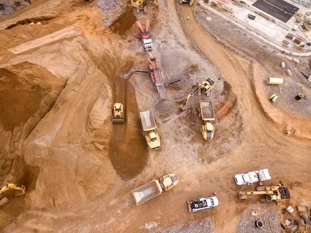 Luftaufnahme einer Erdbaustelle mit Baggern, Muldenkippern und Brechanlage als Bezug zur Kupfermeldung von Trekor Metals