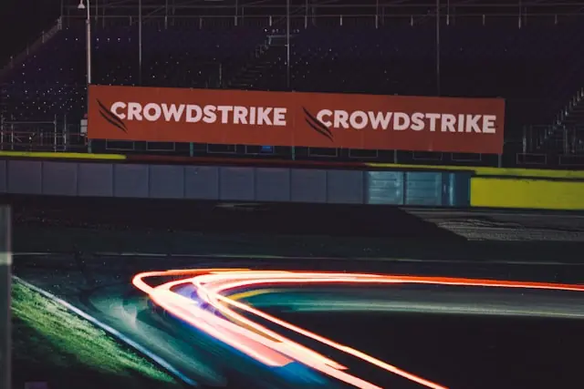 CrowdStrike-Werbebanden an einer nächtlichen Rennstrecke mit Lichtspuren als Bezug zum Cyber-Alarm der US-Behörden