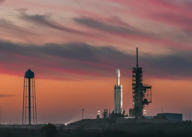 Weiße SpaceX-Rakete auf der Startrampe vor rötlichem Abendhimmel als Bezug zum möglichen Börsengang des Raumfahrtunternehmens