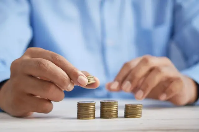 Hände stapeln Münzreihen auf einem Tisch als Bezug zum Börsengang von CoastalSouth Bancshares und dem Wechsel von OTCQX zur NYSE