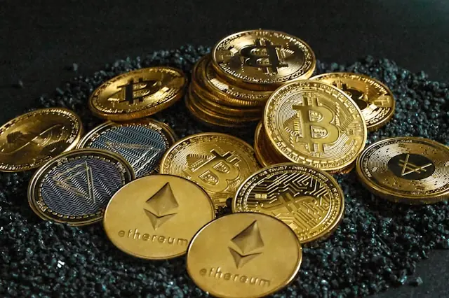 Mehrere Bitcoin-, Ethereum- und weitere Kryptomünzen auf dunklem, körnigem Untergrund im Kontext des Direct Listings von Owlting.