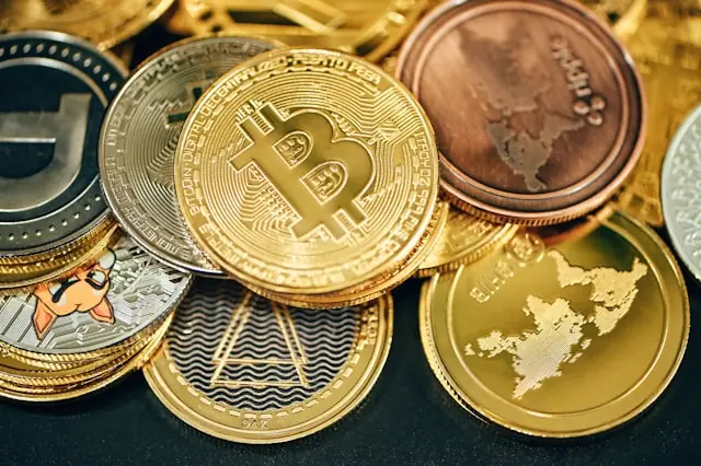 Mehrere physische Kryptowährungsmünzen, darunter eine Bitcoin-Münze im Vordergrund, im Kontext des Börsengangs von BGIN Blockchain.