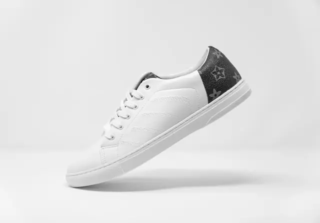 Weißer Ledersneaker mit dunklem Fersenbesatz und Monogramm-Muster freigestellt vor hellem Hintergrund im Zusammenhang mit der Entwicklung am Sneaker-Markt