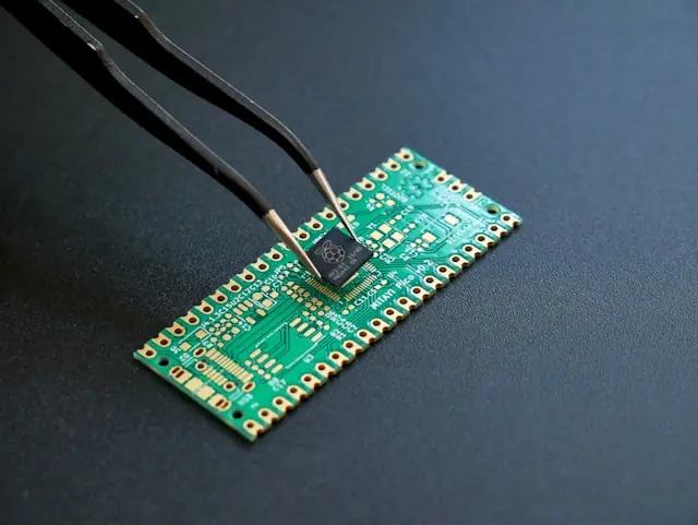 Pinzette an einem Mikrochip auf einer grünen Platine als Bezug zum Kurs-Comeback von AXT nach wochenlangem Ausverkauf